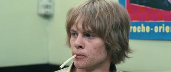 Movie still from “2 or 3 Things I Know About Her” (1967), directed by Jean-Luc Godard – A young man with a cigarette in his mouth; Close Up shot, Low angle