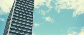 Movie still from “2 or 3 Things I Know About Her” (1967), directed by Jean-Luc Godard – A tall building with a sky background and some clouds; Extreme Wide shot, Low angle
