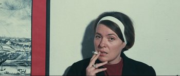 Movie still from “2 or 3 Things I Know About Her” (1967), directed by Jean-Luc Godard – A woman smoking a cigarette while wearing a headband; Close Up shot, High angle