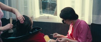 Movie still from “2 or 3 Things I Know About Her” (1967), directed by Jean-Luc Godard – A woman sitting in front of another woman holding a cigarette; Medium shot, Over the shoulder angle