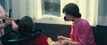 Movie still from “2 or 3 Things I Know About Her” (1967), directed by Jean-Luc Godard – A woman is getting her nails done in a salon; Medium shot, High angle