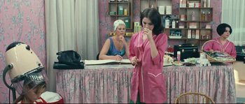 Movie still from “2 or 3 Things I Know About Her” (1967), directed by Jean-Luc Godard – A woman standing in front of a counter in a room; Medium shot, Over the shoulder angle