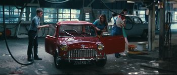 Movie still from “2 or 3 Things I Know About Her” (1967), directed by Jean-Luc Godard – Two women are washing a red car in a garage; Wide shot, High angle
