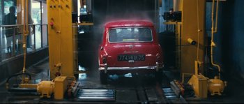 Movie still from “2 or 3 Things I Know About Her” (1967), directed by Jean-Luc Godard – An old red car is being washed in a car wash; Wide shot, High angle