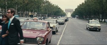 Movie still from “2 or 3 Things I Know About Her” (1967), directed by Jean-Luc Godard – A street filled with lots of traffic and parked cars; Wide shot, Over the shoulder angle