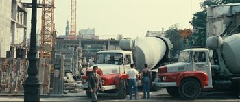Movie still from “2 or 3 Things I Know About Her” (1967), directed by Jean-Luc Godard – A group of men standing next to a cement mixer truck; Extreme Wide shot, High angle