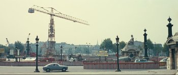 Movie still from “2 or 3 Things I Know About Her” (1967), directed by Jean-Luc Godard – A large crane in the background of a street; Extreme Wide shot, Low angle