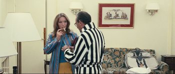 Movie still from “2 or 3 Things I Know About Her” (1967), directed by Jean-Luc Godard – A man and a woman in striped robes in a living room; Medium shot, Over the shoulder angle