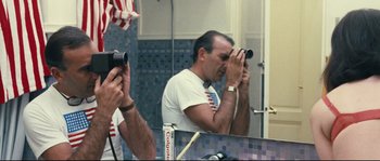 Movie still from “2 or 3 Things I Know About Her” (1967), directed by Jean-Luc Godard – A man taking a picture of himself in the mirror; Medium shot, Low angle