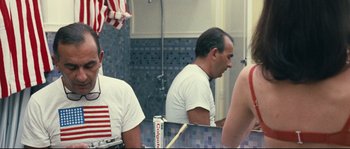Movie still from “2 or 3 Things I Know About Her” (1967), directed by Jean-Luc Godard – A man sitting in front of a mirror in a bathroom; Medium shot, Over the shoulder angle