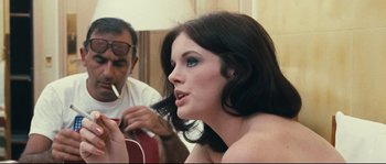 Movie still from “2 or 3 Things I Know About Her” (1967), directed by Jean-Luc Godard – A woman sitting in front of a man with a brush in her mouth; Close Up shot, Over the shoulder angle