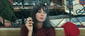Movie still from “2 or 3 Things I Know About Her” (1967), directed by Jean-Luc Godard – A woman smoking a cigarette while sitting in a chair; Close Up shot, High angle