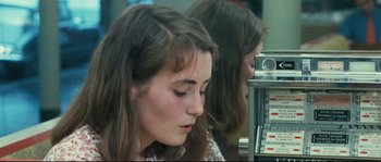 Movie still from “2 or 3 Things I Know About Her” (1967), directed by Jean-Luc Godard – A woman sitting in front of a machine; Close Up shot, Over the shoulder angle