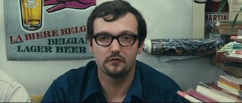 Movie still from “2 or 3 Things I Know About Her” (1967), directed by Jean-Luc Godard – A person wearing glasses and a blue shirt; Close Up shot, High angle