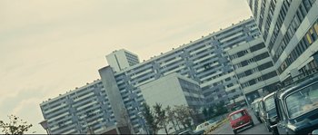 Movie still from “2 or 3 Things I Know About Her” (1967), directed by Jean-Luc Godard – A large building with a parking lot in front of it; Extreme Wide shot, Low angle