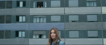 Movie still from “2 or 3 Things I Know About Her” (1967), directed by Jean-Luc Godard – A woman standing in front of a tall building; Wide shot, Low angle