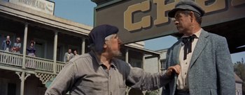 Movie still from “20,000 Leagues Under the Sea” (1954), directed by Richard Fleischer – An older man is standing outside of a building; Medium shot, Over the shoulder angle