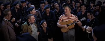 Movie still from “20,000 Leagues Under the Sea” (1954), directed by Richard Fleischer – A group of men are singing and playing a guitar; Medium shot, High angle