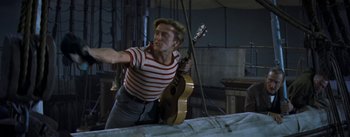 Movie still from “20,000 Leagues Under the Sea” (1954), directed by Richard Fleischer – A man holding a guitar in a room; Medium shot, Low angle