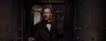 Movie still from “20,000 Leagues Under the Sea” (1954), directed by Richard Fleischer – A man in a suit and bow tie standing next to a door; Medium shot, Low angle