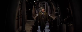 Movie still from “20,000 Leagues Under the Sea” (1954), directed by Richard Fleischer – A man in a suit and tie standing in front of a building; Medium shot, High angle