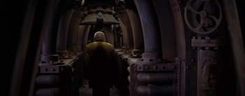 Movie still from “20,000 Leagues Under the Sea” (1954), directed by Richard Fleischer – An older man walking down a hallway in a building; Wide shot, High angle