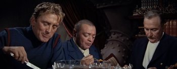 Movie still from “20,000 Leagues Under the Sea” (1954), directed by Richard Fleischer – A man sitting at a table with a plate of food in front of him; Medium shot, Over the shoulder angle