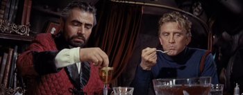 Movie still from “20,000 Leagues Under the Sea” (1954), directed by Richard Fleischer – Two men sitting at a table with a glass of wine; Medium shot, Over the shoulder angle