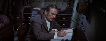 Movie still from “20,000 Leagues Under the Sea” (1954), directed by Richard Fleischer – An older man is writing on a notebook; Medium shot, High angle
