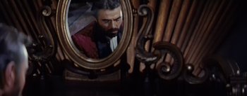 Movie still from “20,000 Leagues Under the Sea” (1954), directed by Richard Fleischer – A man's reflection in a mirror with a pipe rack in the background; Close Up shot, Low angle