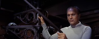 Movie still from “20,000 Leagues Under the Sea” (1954), directed by Richard Fleischer – A man working on an engine in a garage; Medium shot, Low angle