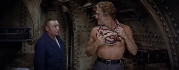 Movie still from “20,000 Leagues Under the Sea” (1954), directed by Richard Fleischer – A man in a red and white striped shirt and a man in a blue suit; Medium shot, Over the shoulder angle