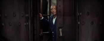 Movie still from “20,000 Leagues Under the Sea” (1954), directed by Richard Fleischer – An old man in a suit standing in front of an open door; Medium shot, High angle