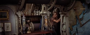 Movie still from “20,000 Leagues Under the Sea” (1954), directed by Richard Fleischer – A man in striped shirt working in a room; Medium shot, High angle