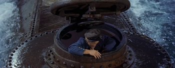 Movie still from “20,000 Leagues Under the Sea” (1954), directed by Richard Fleischer – A man is looking into an old fashioned machine; Wide shot, Overhead angle