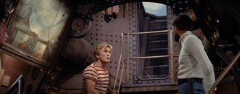 Movie still from “20,000 Leagues Under the Sea” (1954), directed by Richard Fleischer – A man in striped shirt sitting in front of stairs; Medium shot, Low angle