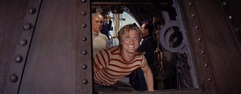 Movie still from “20,000 Leagues Under the Sea” (1954), directed by Richard Fleischer – A man in a striped shirt is looking out of a window; Medium shot, Low angle