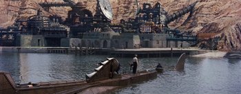 Movie still from “20,000 Leagues Under the Sea” (1954), directed by Richard Fleischer – A man is standing on the back of a boat in the middle of the water; Extreme Wide shot, High angle
