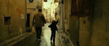 Movie still from “22 Bullets” (2010), directed by Richard Berry – A little boy and a dog walking down a street; Wide shot, Low angle