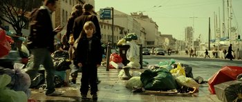 Movie still from “22 Bullets” (2010), directed by Richard Berry – A young boy standing on the side of the street; Wide shot, Low angle