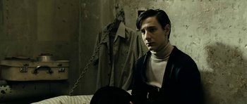 Movie still from “22 Bullets” (2010), directed by Richard Berry – A man standing next to a bed in a room; Medium shot, Low angle