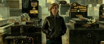 Movie still from “22 Bullets” (2010), directed by Richard Berry – A man in a leather jacket standing in front of a cemetery; Medium shot, Low angle
