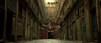 Movie still from “22 Bullets” (2010), directed by Richard Berry – An alleyway with a mural on the side of the building; Extreme Wide shot, Low angle