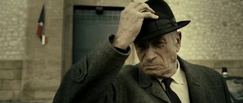 Movie still from “22 Bullets” (2010), directed by Richard Berry – An old man wearing a suit and a hat; Close Up shot, Low angle