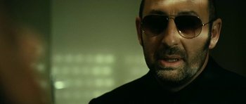 Movie still from “22 Bullets” (2010), directed by Richard Berry – A person wearing sunglasses; Close Up shot, Low angle