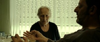 Movie still from “22 Bullets” (2010), directed by Richard Berry – An older woman sitting in front of a man; Close Up shot, Over the shoulder angle
