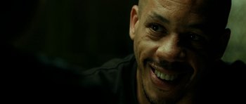 Movie still from “22 Bullets” (2010), directed by Richard Berry – A man smiling for the camera; Close Up shot, Low angle
