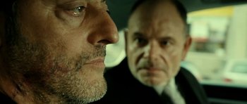 Movie still from “22 Bullets” (2010), directed by Richard Berry – A man and a man in a car looking at each other; Close Up shot, Over the shoulder angle