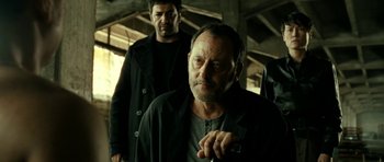 Movie still from “22 Bullets” (2010), directed by Richard Berry – A man in a black jacket and another man in a black jacket; Medium shot, Low angle