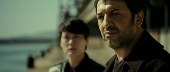 Movie still from “22 Bullets” (2010), directed by Richard Berry – A man and a woman standing next to each other; Close Up shot, Over the shoulder angle